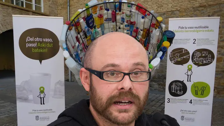 El concejal Cuenca y, detrás, los carteles presentados por el Ayuntamiento para impulsar el vaso reutilizable en San Fermín.