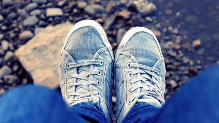 Un chico con vaqueros y zapatillas descansa en el camino. 