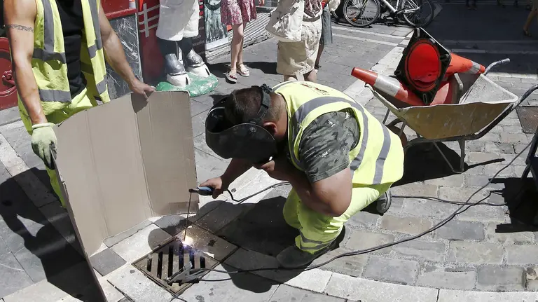 Dos trabajadores proceden al sellado de las arquetas en Pamplona. EFE/Jesús Diges