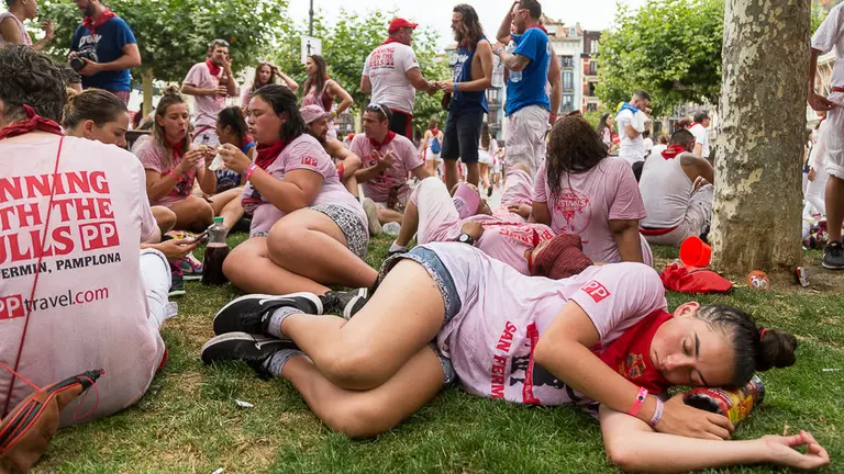 Una joven duerme en pleno Chupinazo de los Sanfermines en los jardines de la Plaza del Castillo de Pamplona. IÑIGO ALZUGARAY