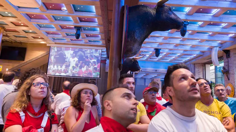 Un grupo de personas presencia en un bar de Pamplona el encierro de Sanfermines que está teniendo lugar a escasos metros del local. EFE/EPA/JIM HOLLANDER
