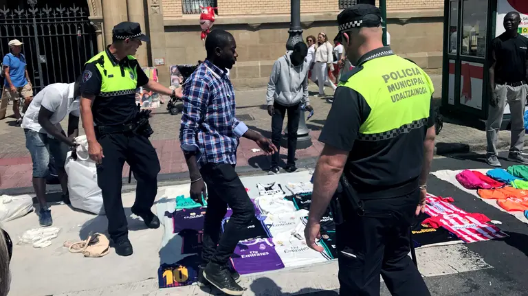Agentes de la Policía Municipal de Pamplona junto a manteros que trabajan en la venta ambulante durante los Sanfermines 2017 (2)