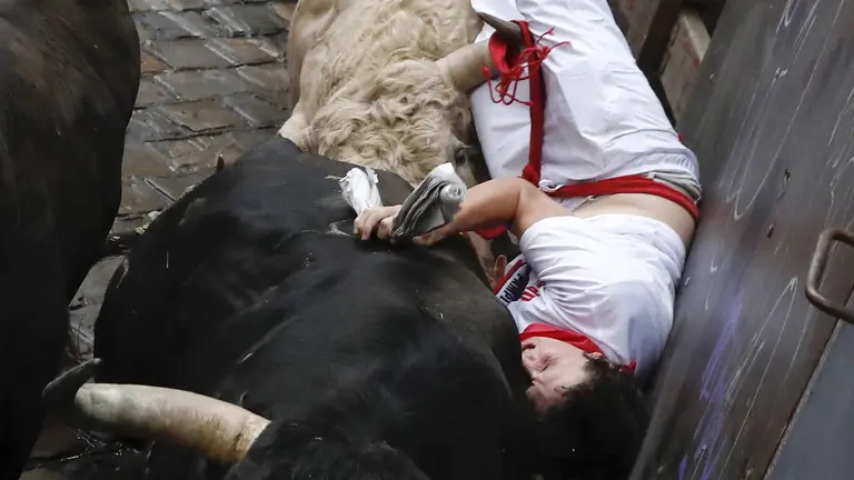 Un mozo sufre una cogida en la curva de Mercaderes durante el quinto encierro de los Sanfermines 2017, que ha sido el más rápido hasta ahora con una duración de dos minutos y doce segundos, y que ha finalizado, en principio, sin heridos por asta de toro. EFE/Villar López