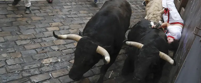GRA020. PAMPLONA, 11/07/2017.- Un mozo sufre una cogida en la curva de Mercaderes durante el quinto encierro de los Sanfermines 2017, que ha sido el más rápido hasta ahora con una duración de dos minutos y doce segundos, y que ha finalizado, en principio, sin heridos por asta de toro. EFE/Villar López