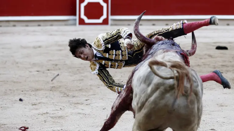 GRA428. PAMPLONA, 11/07/2017.- El diestro peruano Andrés Roca Rey volteado al entrar a matar al segundo de su lote, durante el séptimo festejo de los Sanfermines, en el que comparte cartel con los matadores, Cayetano Rivera y Miguel Ángel Perera, lidiando toros de Jandilla. EFE/Jesús Diges