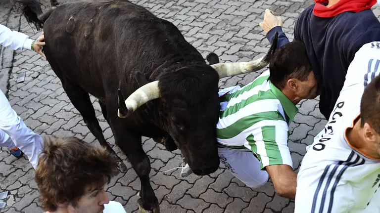 GRA025. PAMPLONA, 12/07/2017.- Uno de los toros de la ganadería madrileña de Victoriano del Río tira a un joven en el tramo en Telefónica, durante el sexto encierro de los Sanfermines 2017. EFE/ Daniel Fernández