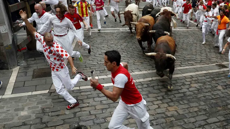 GRA028. PAMPLONA, 13/07/2017.- Los toros de la ganadería gaditada de Núñez del Cuvillo a su paso por la curva de Mercaderes durante el séptimo encierro de los San Fermines 2017, en el que las reses han protagonizado una rápida carrera de dos minutos y diez segundos hasta la arena de la plaza, y en la que, hasta el momento, se han contabilizado dos heridos por asta y un contusionado. EFE/Javier Lizón