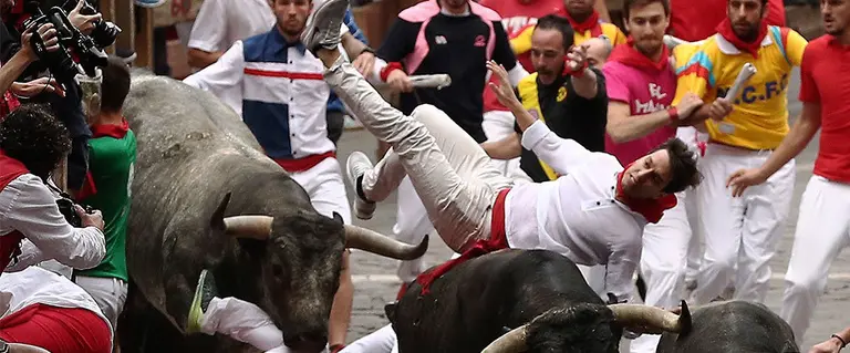 Un mozo es volteado por la manada de los miuras en la bajada al callejón de la plaza de toros. EFE.
