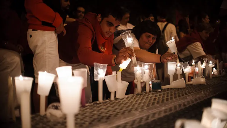 Los pamploneses dejan velas y pañuelos a las puertas de la parroquia de San Lorenzo, donde se encuentra la capilla de San Fermín. MIGUEL OSÉS