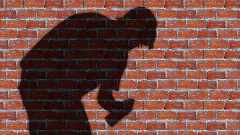 Silueta de una persona con un spray para hacer una pintada en un muro.