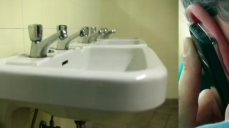 A la izquierda, unos lavabos y, a la derecho, un hombre habla por teléfono móvil