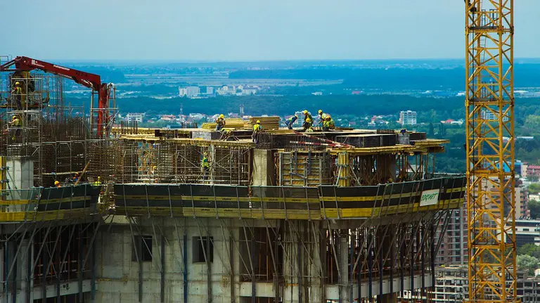 Construcción de una torre de pisos con varias grúas y albañiles trabajando sobre la azotea ARCHIVO