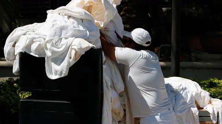 Trabajador transportando prendas para lavar en un hospital. ARCHIVO