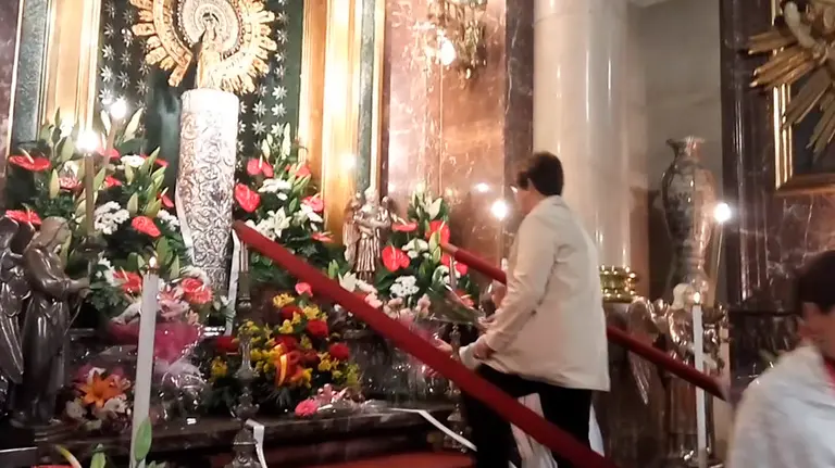 Una mujer coloca flores a la Virgen del Pilar de San Nicolás