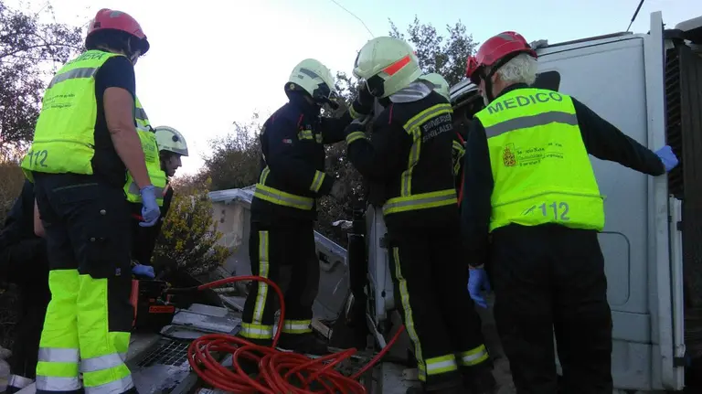 Un equipo de bomberos socorre al conductor herido en un accidente entre dos camiones en la zona de El Carrascal.