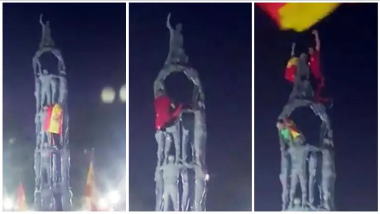 Un joven escala el monumento de los Castellers en Tarragona para colocar una bandera de España.