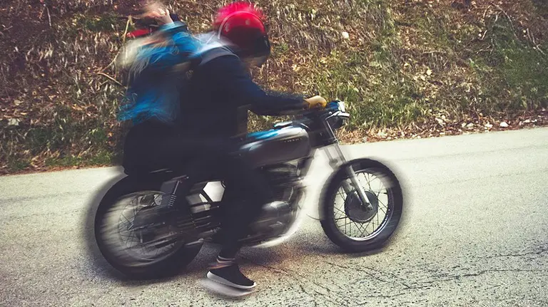 Un motorista junto a una chica en el asiento trasero
