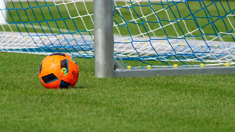 Un balón de fútbol junto a una portería