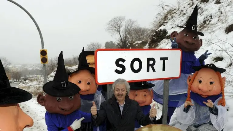 El propetario de La Bruixa d'Or, Xavier Gabriel, posa junto al cartel de la localidad catalana de Sort EFE