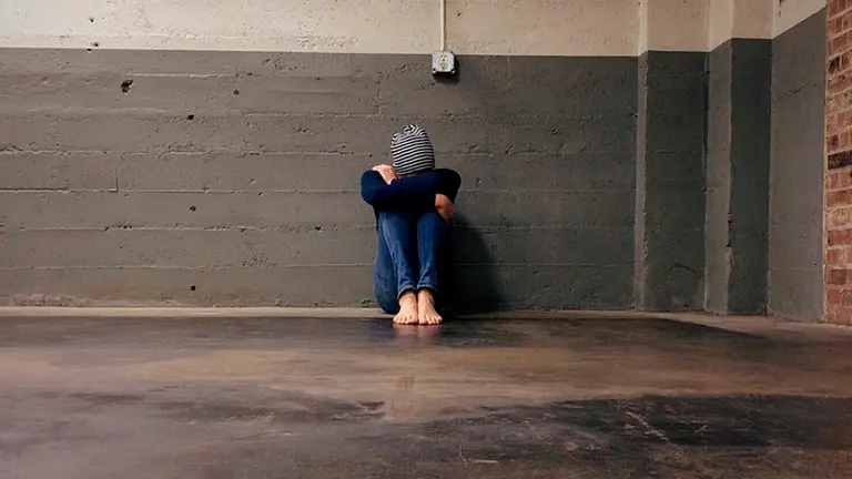 Una joven yace en el suelo cabizbaja