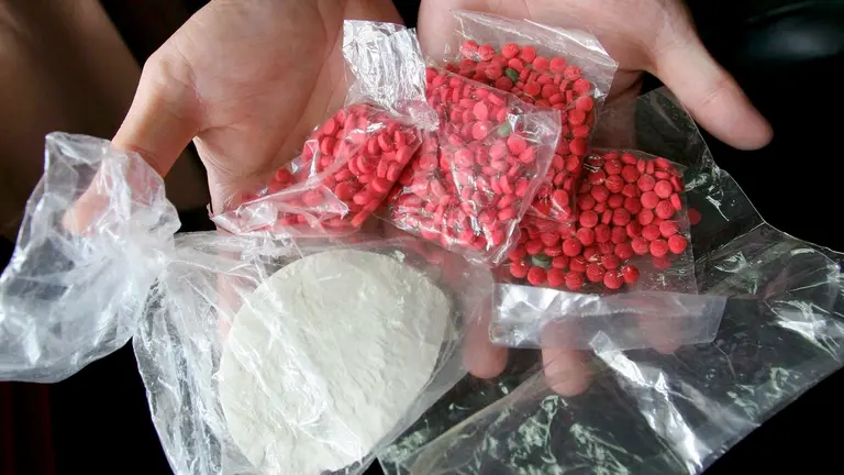 Una persona sostiene varias bolsas con drogas.