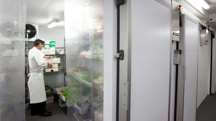 Un trabajador manipula varios alimentos en el interior de una cámara frigorífica