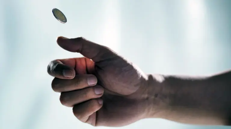 Una persona lanza una moneda al aire.