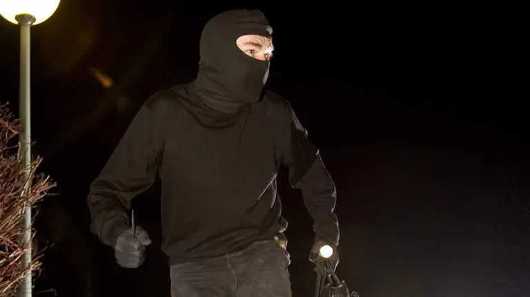 Imagen de un ladrón escapando de un atraco con la cara tapada por un pasamontañas