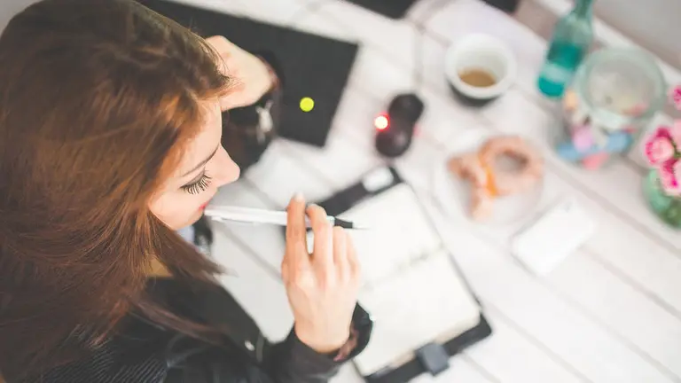 Una joven anotando una reunión de trabajo en una agenda en la oficina