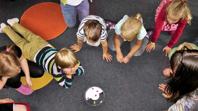 Varios niños atienden las explicaciones de una profesora en el colegio ARCHIVO