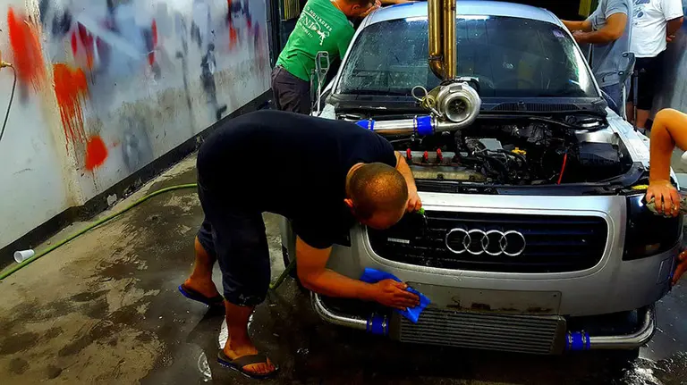 Varios mec&aacute;nicos reparan un coche