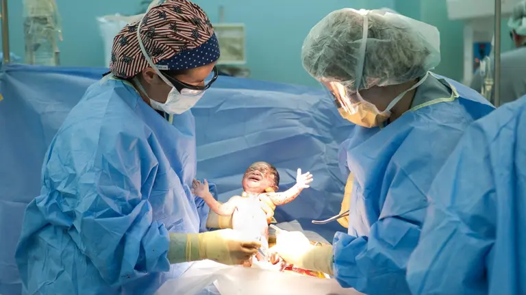 PORT-AU-PRINCE, HAITI - JANUARY 21: Doctors Susan Farrar (L) and Shannon Lamb (R) deliver a baby girl named Esther by C-section on board the USNS Comfort, a U.S. Naval hospital ship, on January 21, 2010 in Port-au-Prince, Haiti. Esther is the first baby ever born on the ship; her mother suffered a crushed pelvis during Haiti's recent earthquake. The Comfort deployed from Baltimore with 550 medical personnel on board to treat earthquake victims and arrived in Haiti on January 20. (Photo by Brendan Hoffman/Getty Images) *** Local Caption *** Susan Farrar;Shannon Lamb