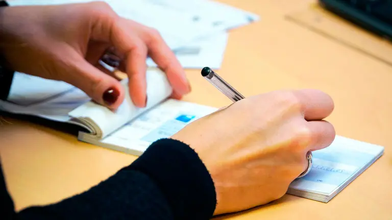 Una persona firma un cheque. ARCHIVO