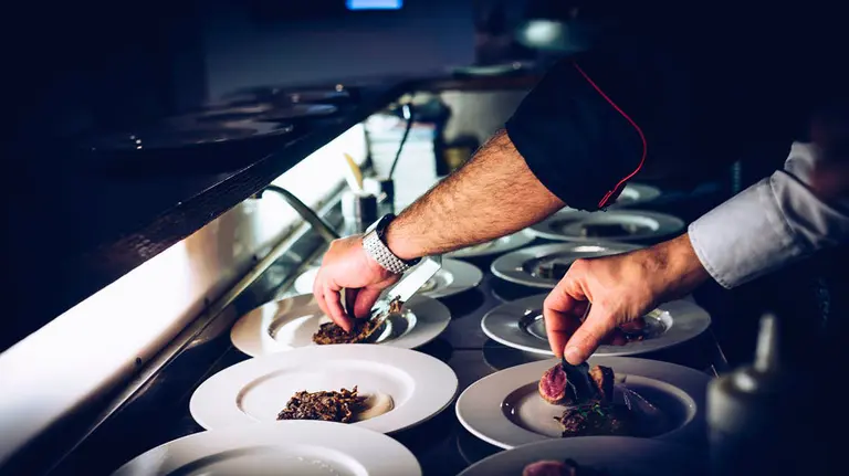 Un cocinero y su ayudante preparan una serie de platos en la cocina de un restaurante. ARCHIVO