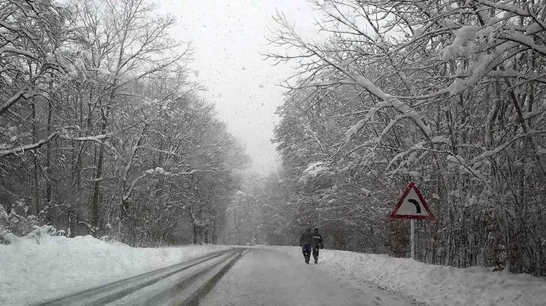 Dos personas caminan por la N-135 en el término de Roncesvalles (Navarra), comunidad donde continúa el temporal de nieve con esperoses que alcanzan los 50cm de nieve. EFE/Villar López