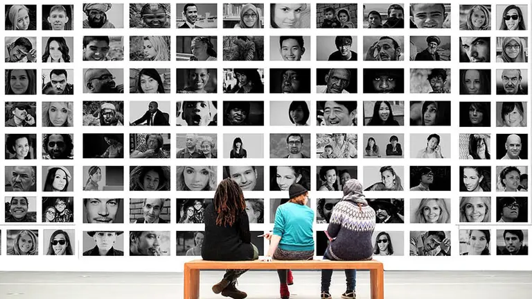 Varias personas observan una exposición sobre fotografías de otras personas