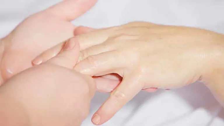 Una persona masajea la mano de otra. ARCHIVO