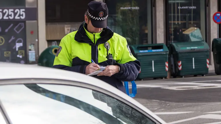 Un policía municipal multa a un vehículo en la zona restringida al tráfico y aparcamiento en la calle Padre Moret junto al Parlamento de Navarra (04). IÑIGO ALZUGARAY