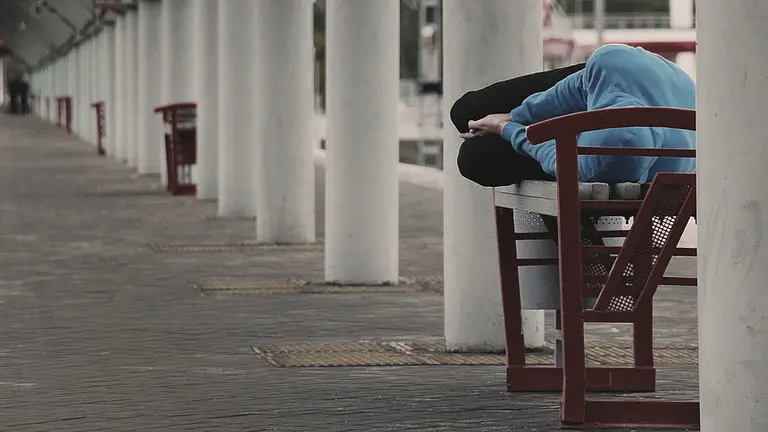 Un vagabundo duerme en un banco al aire libre ARCHIVO
