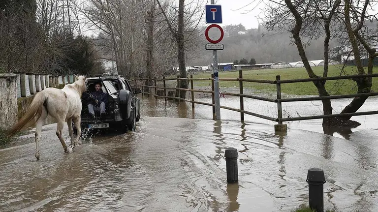 GRAF5633. PAMPLONA (NAVARRA) 20/02/2018.- Un joven montado en un vehículo ayuda a un caballo a pasar por una carretera inundada junto a las huertas de la Magdalena donde el río Arga ha comenzado a desbordarse tras la lluvia de estos últimos días y el consiguiente deshielo de la nieve que de forma abundante se mantiene en el monte. EFE/Jesús Diges