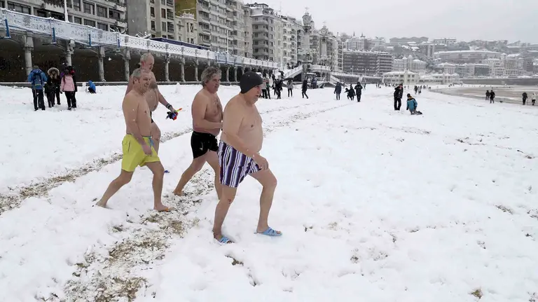 GRAF1482. SAN SEBASTIÁN, 28/02/2018.- Un grupo de bañistas se dirigen al agua en la bahía de la Concha de San Sebastián. Cuarenta provincias de catorce comunidades continúan hoy en alerta por el temporal que deja bajas temperaturas, riesgo de aludes, intenso oleaje, rachas intensas de viento y fuertes nevadas de hasta 35 centímetros de espesor en zonas de montaña, informa la Agencia de Meteorología (Aemet) en su web. Aragón tiene activada la alerta naranja (riesgo importante) en Huesca y Zaragoza por nevadas que dejarán acumulaciones entre los 5 y 35 centímetros en áreas de las Cinco Villas, Ribera del Ebro y Pirineo oscense, y aviso amarillo en Huesca por viento, aludes y temperaturas mínimas, y en Teruel por nieve. Las comunidades de Navarra, La Rioja y País Vasco continúan en alerta naranja por nevadas, viento o aludes mientras que en Galicia hay aviso naranja por nieve en Lugo y Orense y por fuerte oleaje que alcanzará entre los 5 y 6 metros en el litoral de A Coruña. EFE/ Juan Herrero