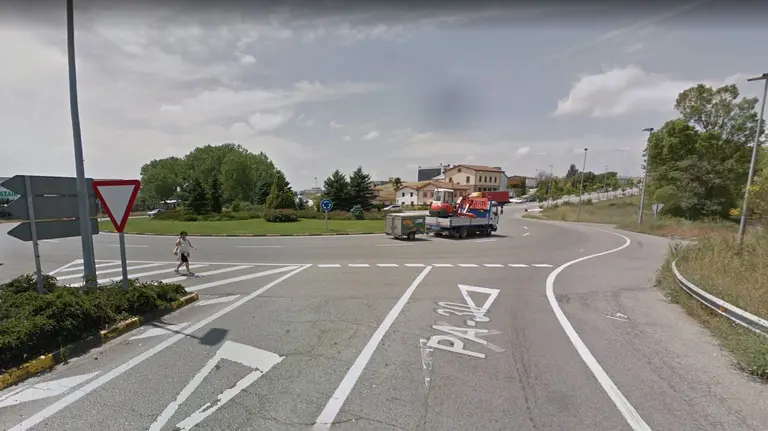 Un señora cruzan por una isleta de una rotonda de la PA-30 al carecer de paso peatonal. NAVARRA.COM