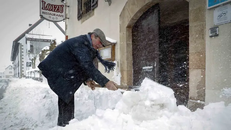 Un vecino de la localidad navarra de Burguete retira la nieve caída en la puerta de su restaurante donde el último temporal de nieve, frío y viento ha acumulado espesores de hasta 30 cm y mantiene a toda la comunidad Foral en alerta por nieve. EFE/Villar López