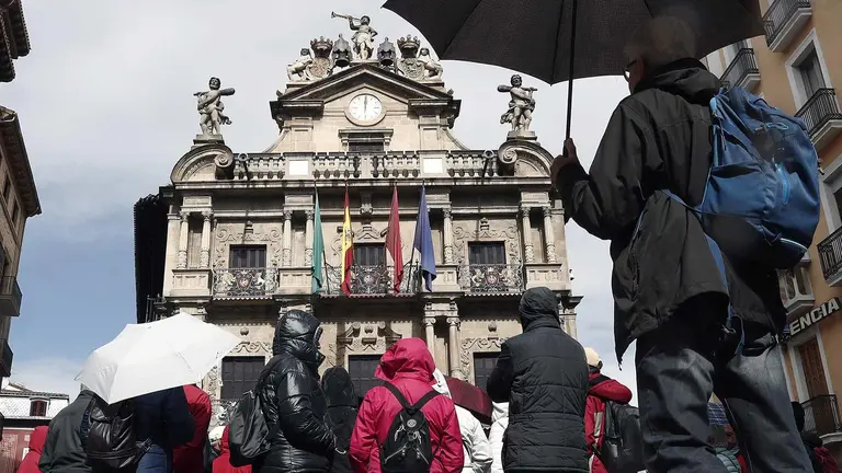GRAF2470. PAMPLONA (ESPAÑA), 29/03/2018.- Un grupo de turistas se protegen con sus paraguas de la lluvia junto al Ayuntamiento de Pamplona en una jornada festiva donde la comunidad foral es uno de los lugares preferidos para pasar estos días de Semana Santa. La AEMET anuncia para hoy en Navarra cielos cubiertos con precipitaciones débiles en el tercio norte donde los claros se irán abriendo a lo largo de la jornada. EFE/Jesús Diges