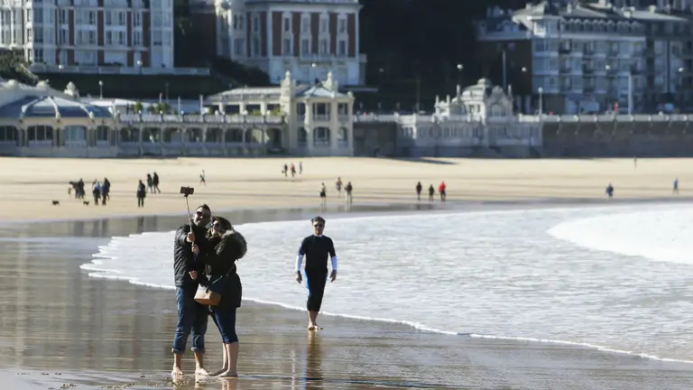 Dos turistas se hacen un selfi en el borde la playa de La Concha en San Sebastián Foto EFE Javier Etxezarreta