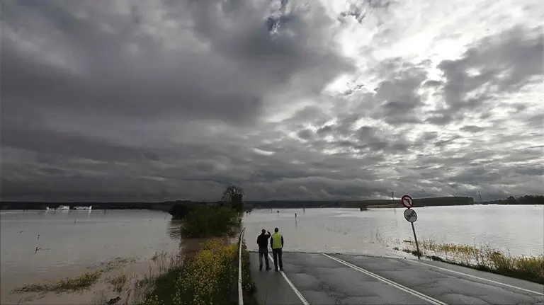 GRAF2865. TUDELA (NAVARRA), 13/04/2018.- Dos personas toman imagenes de la carretera N-113 que permanece cortada hacia Castejón tras el desbordamiento del Rio Ebro.La alerta por inundaciones se mantiene a estas horas en Navarra en dos estaciones de aforo, la del Ebro en Castejón y la del Ega en Andosilla, mientras que en Pamplona desciende el caudal de los ríos y se va recuperando la normalidad tras los desbordamientos de ayer. EFE/ Jesús Diges