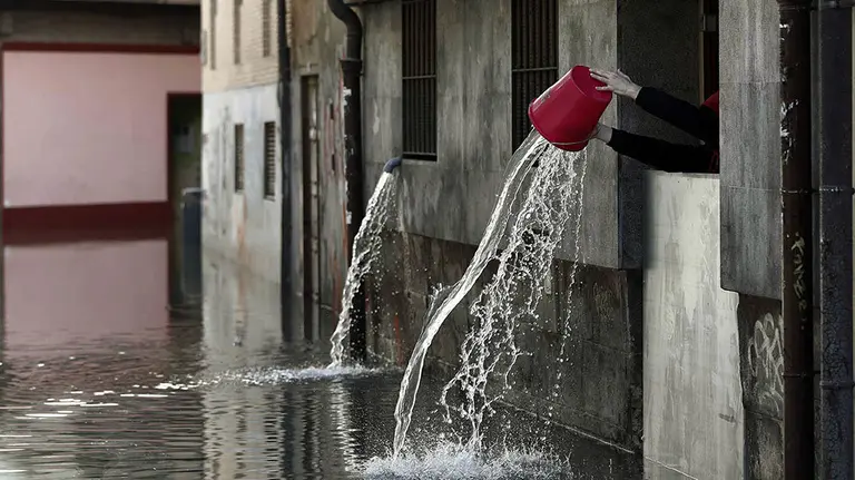 GRAF3184. TUDELA(PAMPLONA) (ESPAÑA), 13/04/2018.- Una persona vierte el agua recogida que ha entrado en las cocinas de un restaurante de Tudela, tras la inundación que ha sufrido el casco viejo de la ciudad por la crecida del rio Ebro. La alerta por inundaciones se mantiene a estas horas en Navarra en dos estaciones de aforo, la del Ebro en Castejón y la del Ega en Andosilla, mientras que en Pamplona desciende el caudal de los ríos y se va recuperando la normalidad tras los desbordamientos de ayer. EFE/Jesús Diges