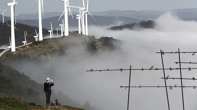 Un peregrino del Camino de Santiago toma una fotografía desde el Alto de El Perdón donde se puede observar el manto de nubes en un tiempo marcado por las altas temperaturas y cielos cubiertos. EFE/Jesús Diges