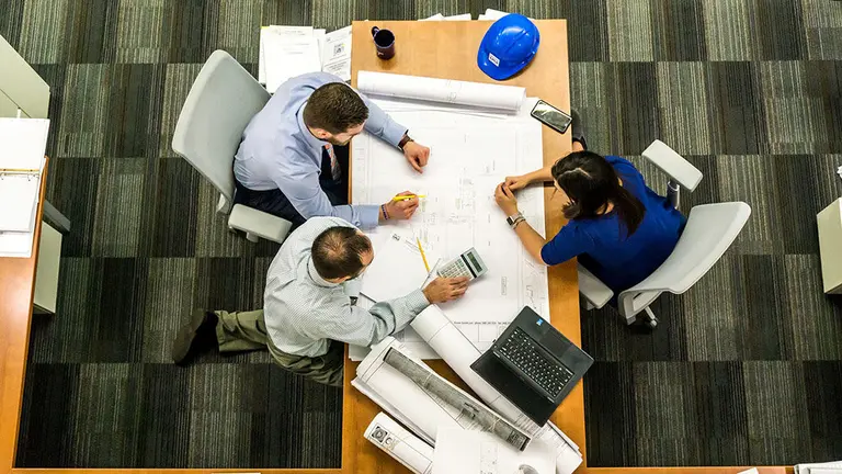 Tres ingenieros trabajan sobre varios planos. ARCHIVO
