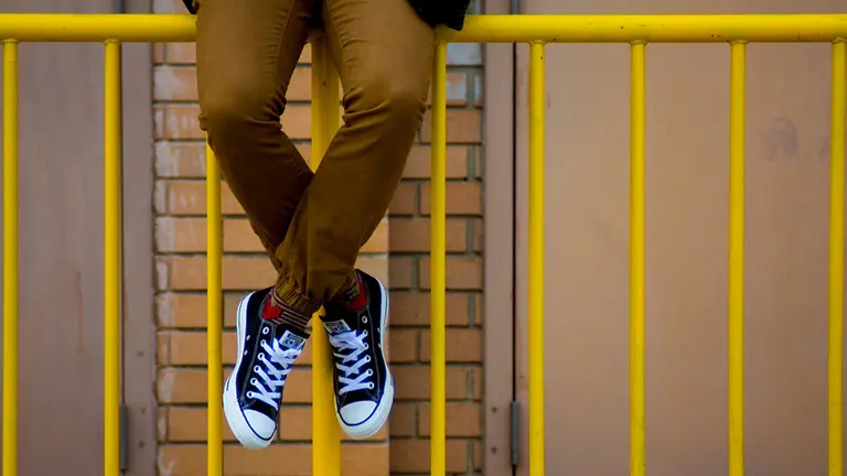 Un alumno sentado en una valla a la salida de un colegio ARCHIVO